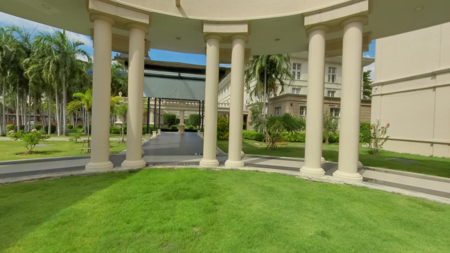 School courtyard with cream columns, covered walkways, palms and a green lawn