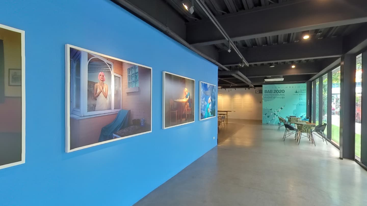 Art exhibition with framed works on a blue gallery wall