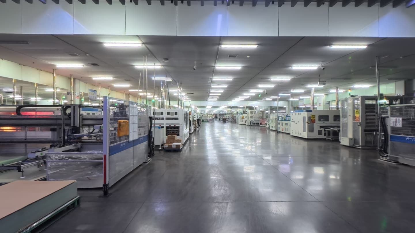 Solar panel production equipment along a brightly lit factory aisle