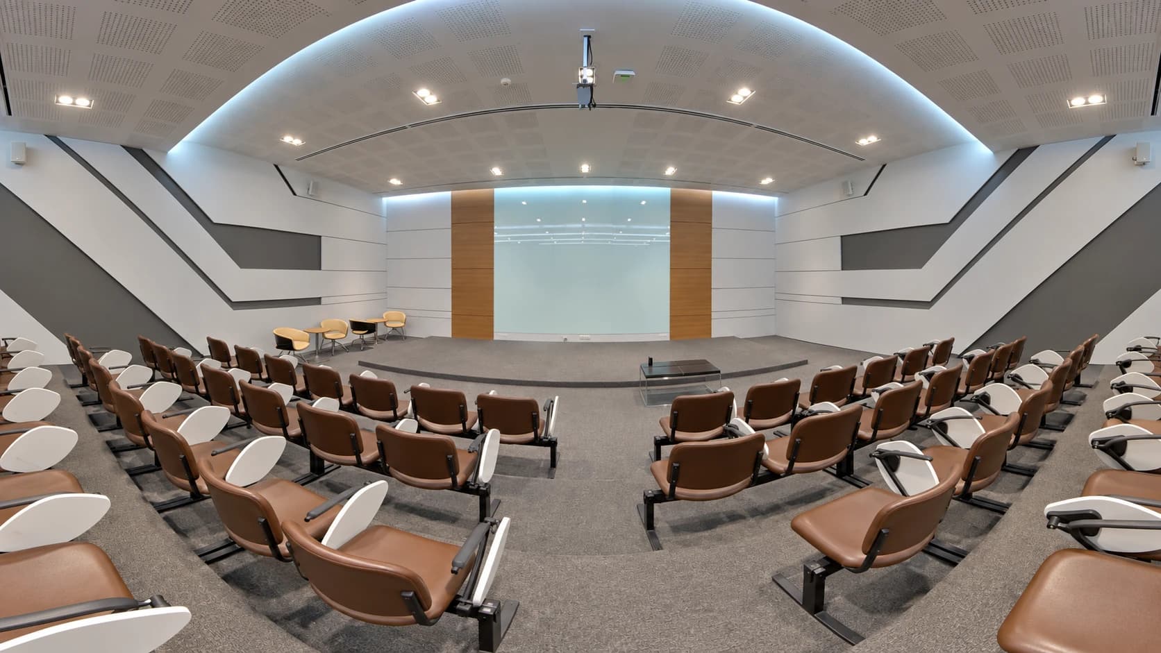 Auditorium with brown seats, white writing tablets and geometric acoustic panels