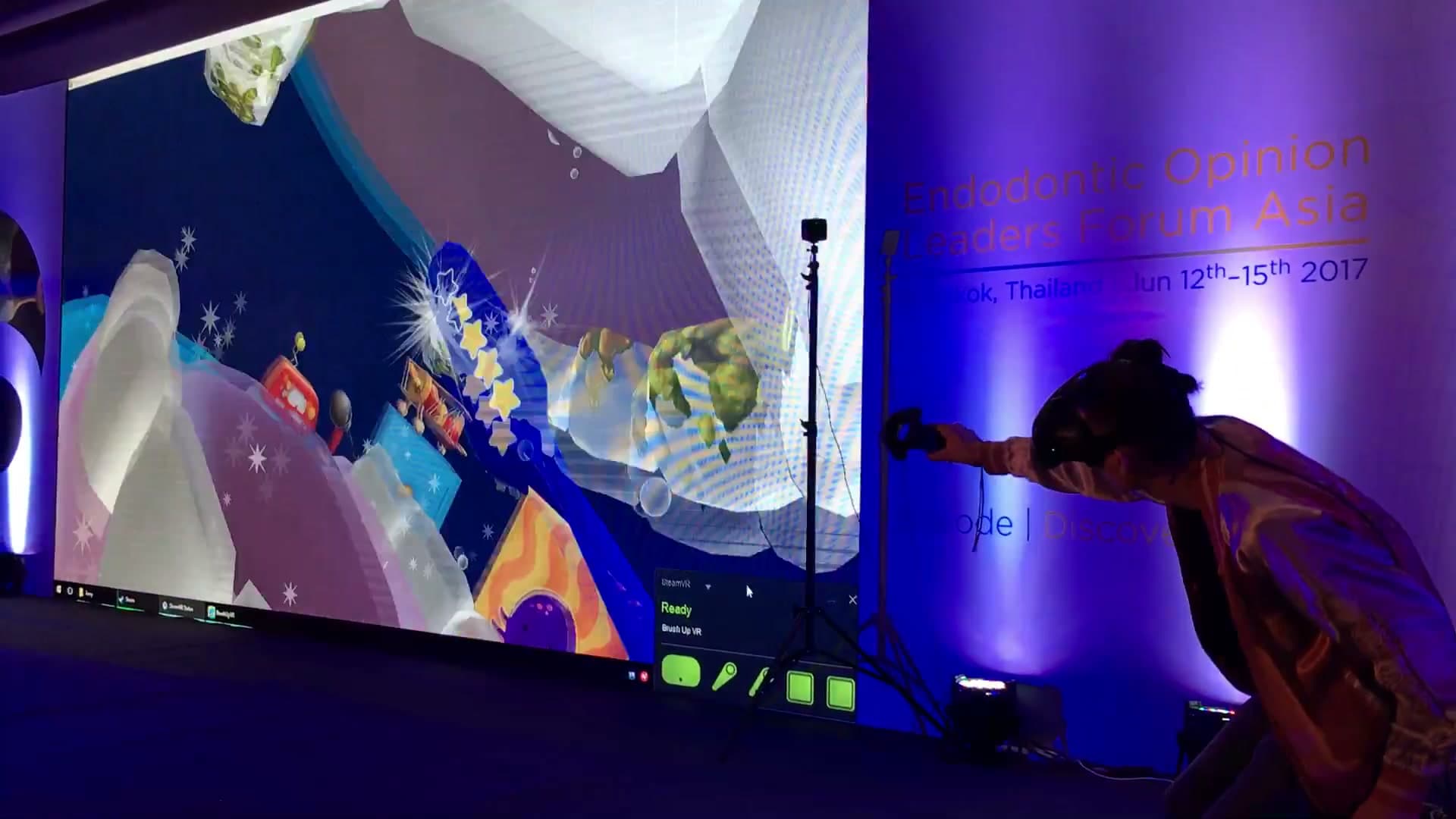 A dinner guest playing a VR toothbrushing game beside the projected gameplay at the Peninsula Bangkok.
